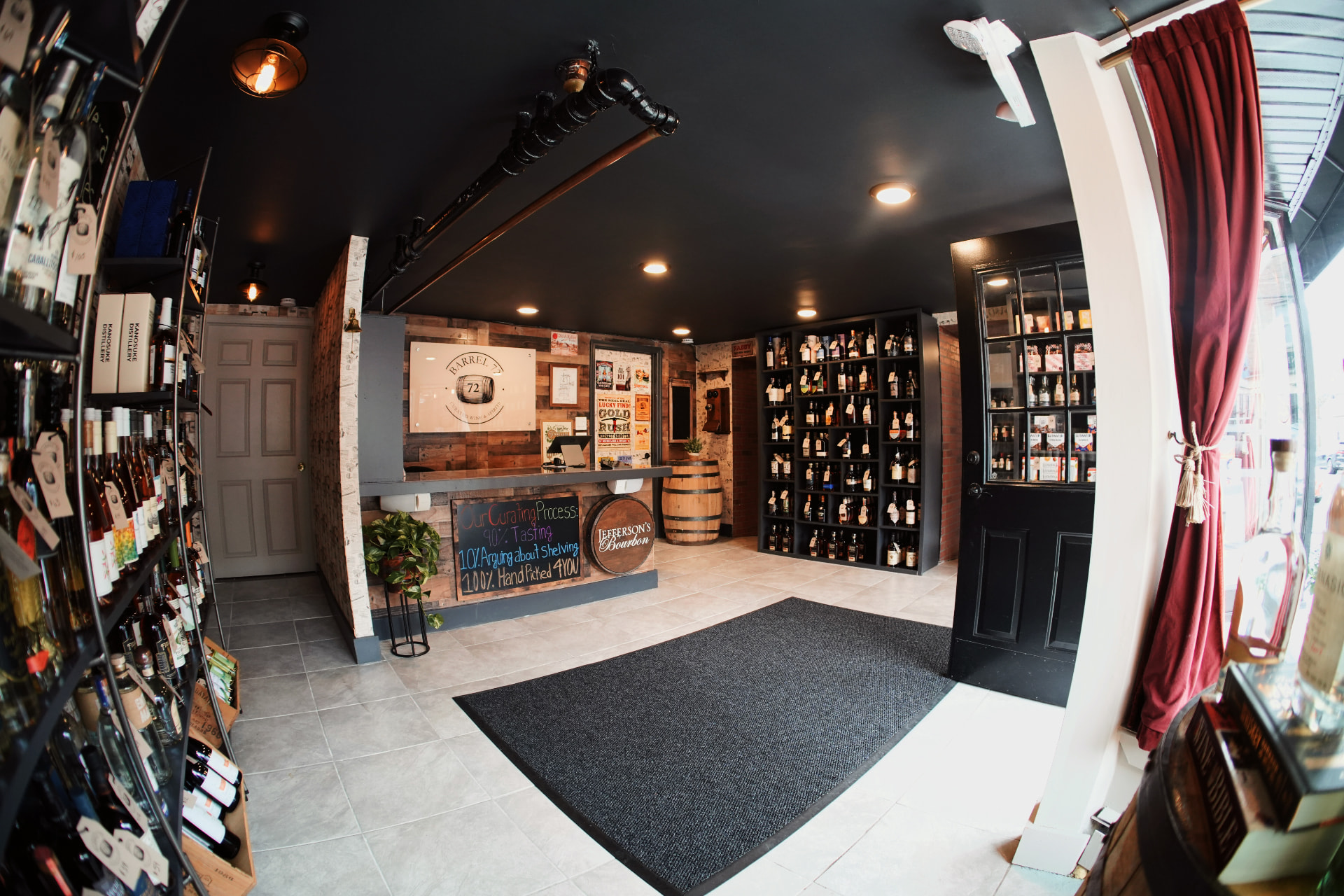 A wide view inside Barrel 72 from the front door, showing the wine shelves, a red curtain and the barrel-front counter