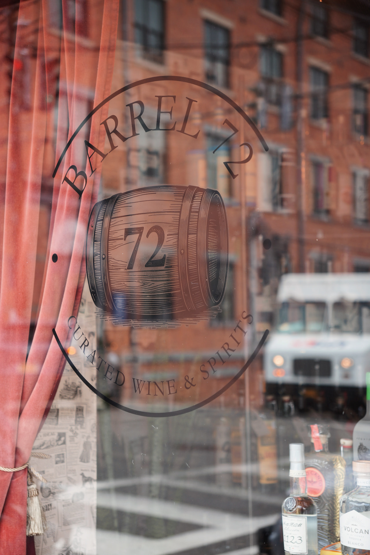 The Barrel 72 barrel logo painted on the shop window, with a Dobbs Ferry street reflected in the glass