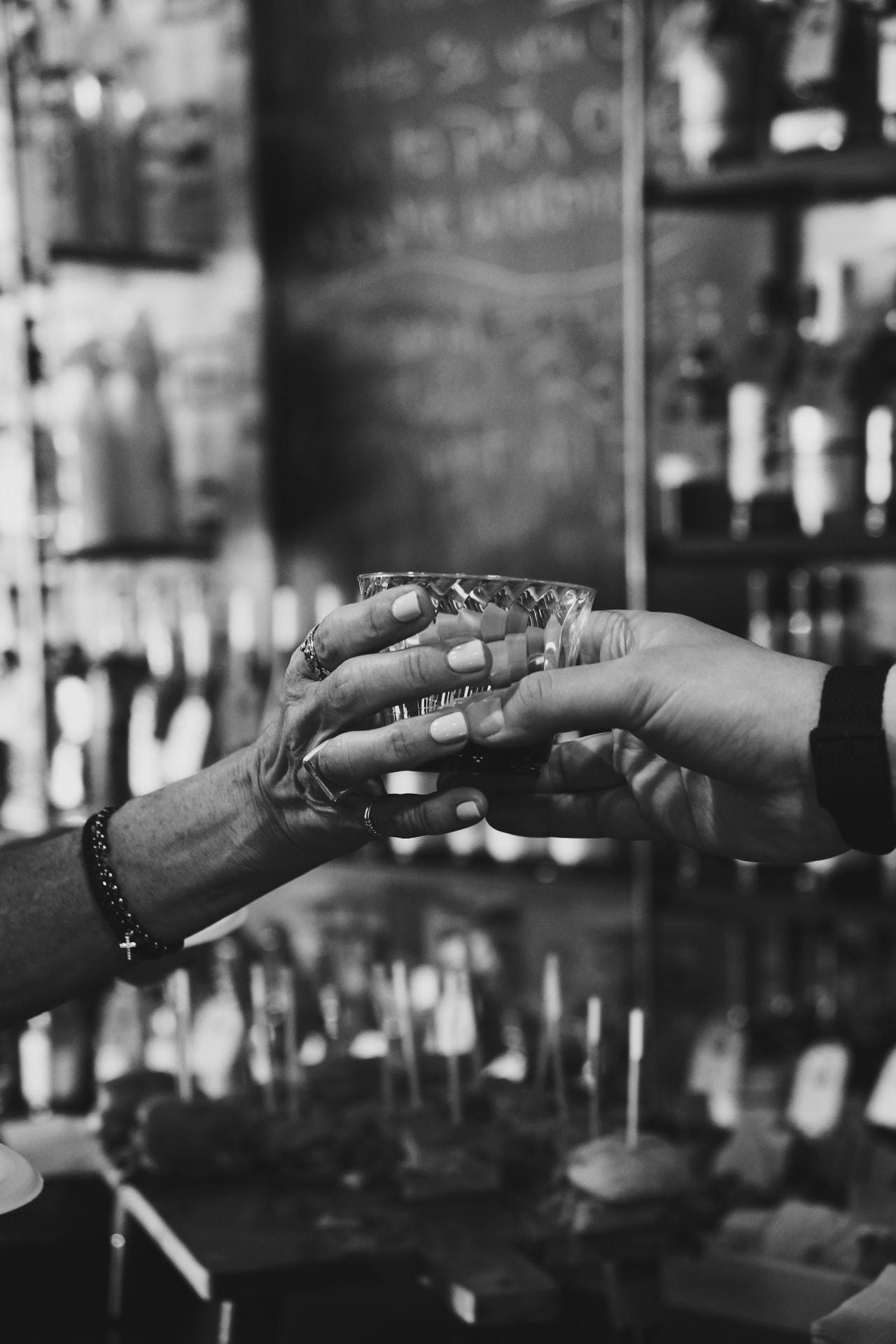 Black-and-white photo of two hands clinking glasses across the Barrel 72 counter