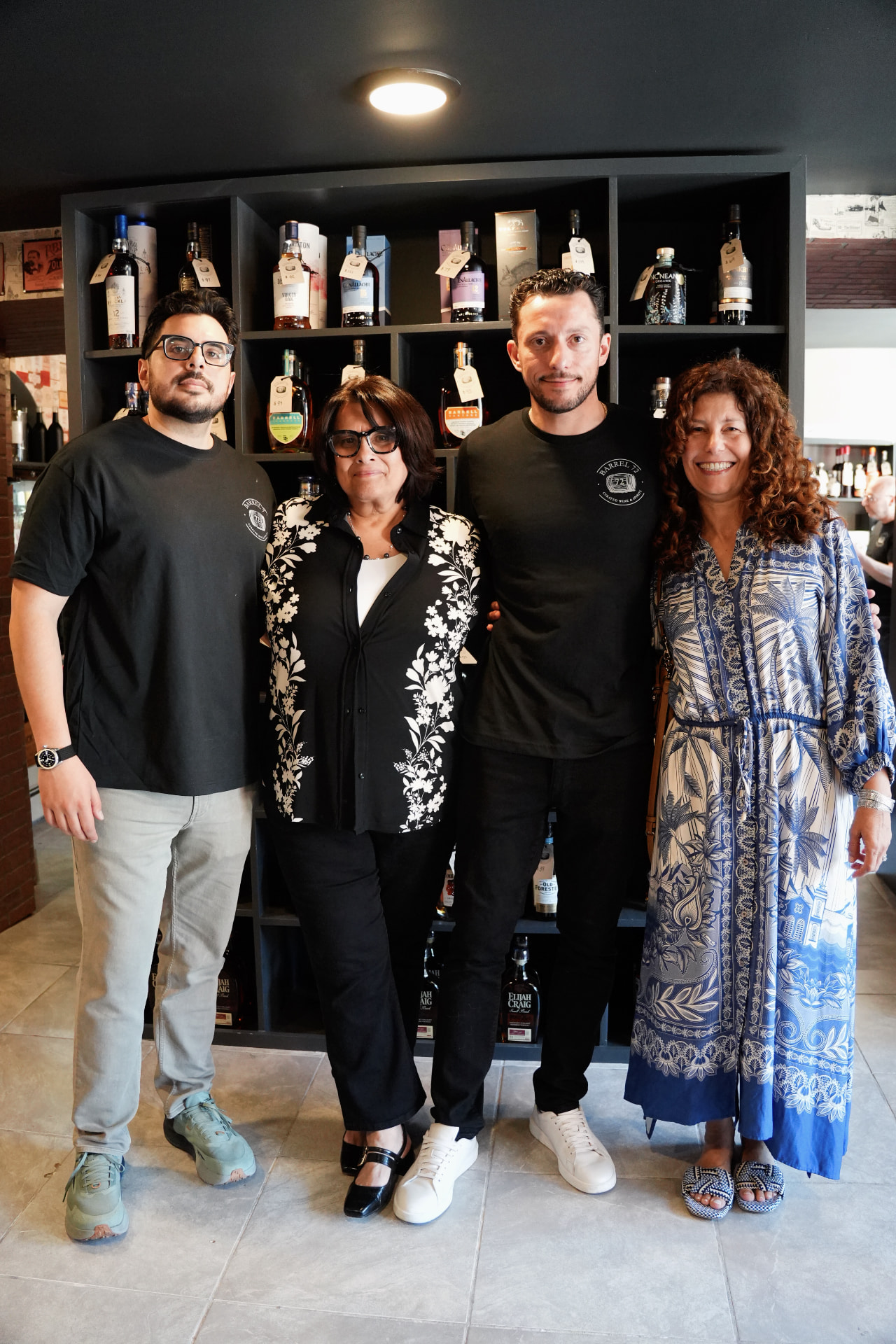 Four smiling members of the Barrel 72 team standing in front of a spirits shelf