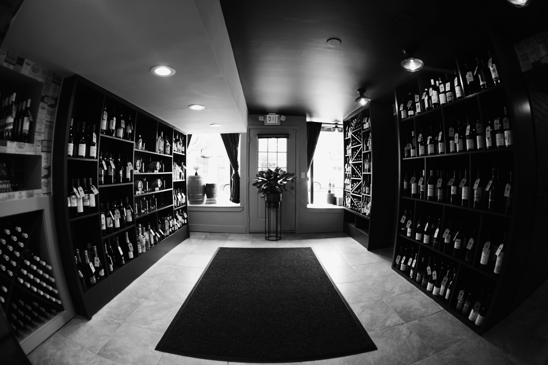 Black-and-white wide view of the Barrel 72 wine room, with dark shelves of bottles on both sides